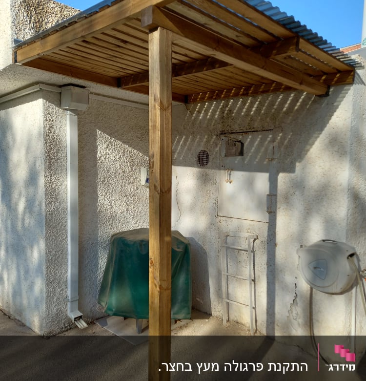 פרגולה מעץ עם גג מתכת ליד קיר חיצוני